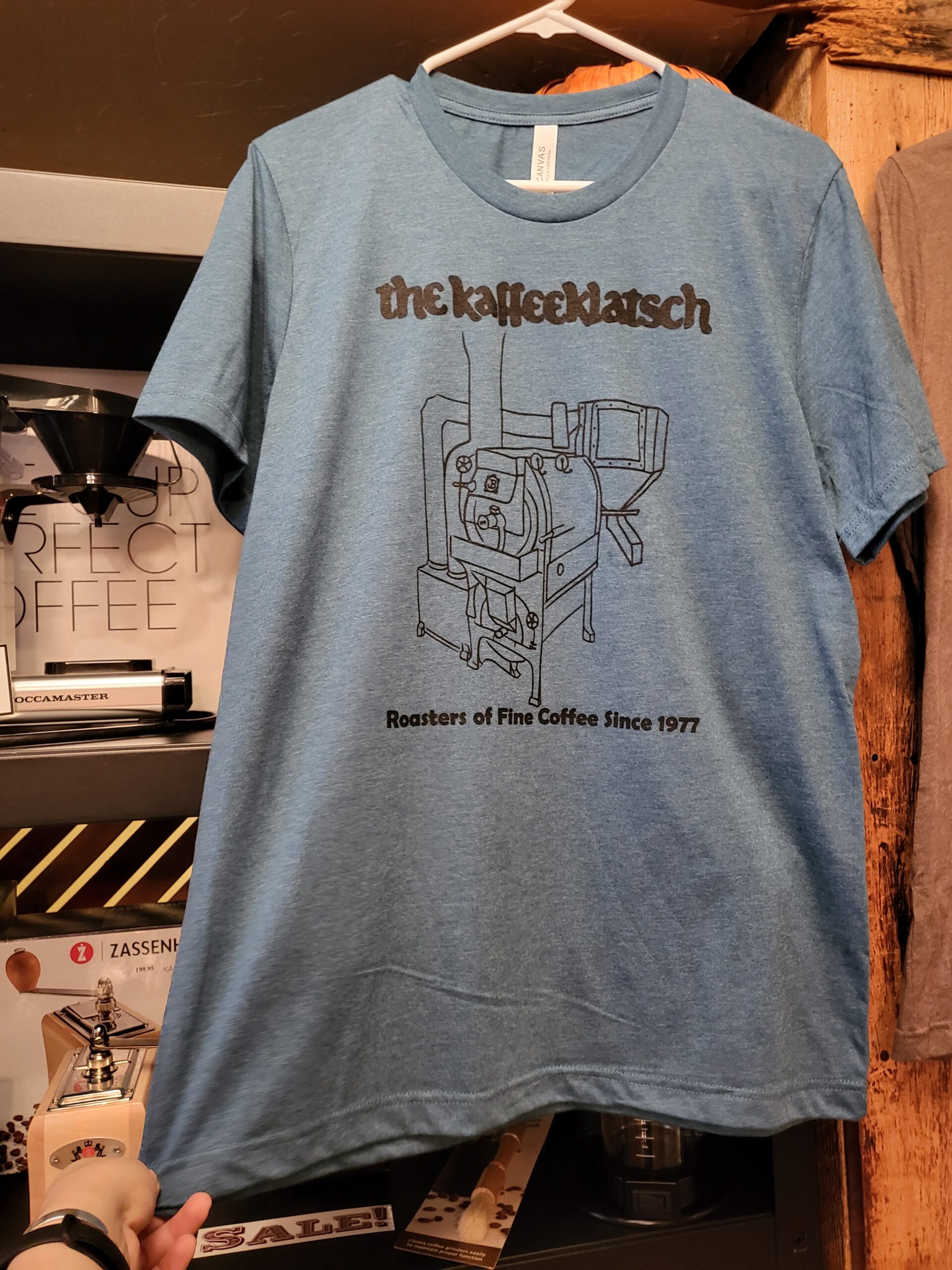 https://www.kaffeeklatsch.com/kaffeeshop/wp-content/uploads/2023/10/heather-teal-shirt-scaled.jpg